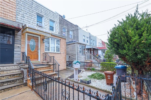 view of front of home featuring fence, entry steps, and mansard roof