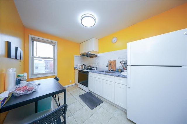 kitchen featuring tasteful backsplash, light stone countertops, freestanding refrigerator, white cabinets, and a sink