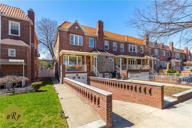 view of front facade featuring a tile roof, a garage, a residential view, a chimney, and fence