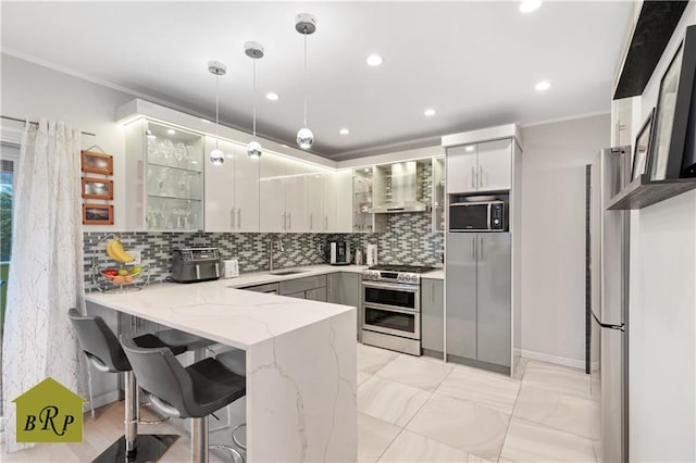 kitchen with tasteful backsplash, stainless steel appliances, light stone countertops, wall chimney exhaust hood, and a peninsula