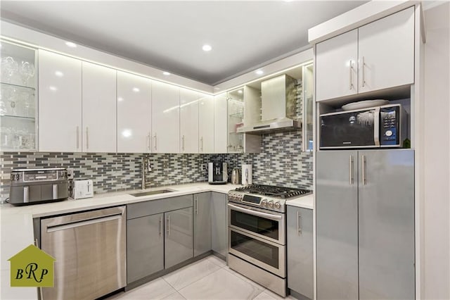 kitchen with a sink, stainless steel appliances, tasteful backsplash, wall chimney exhaust hood, and light countertops