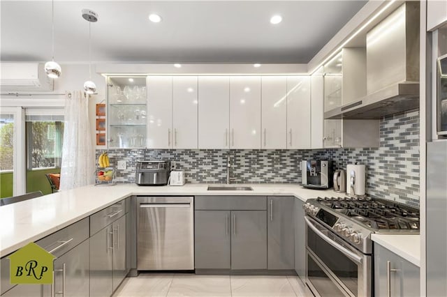 kitchen with a sink, wall chimney range hood, stainless steel appliances, and gray cabinets