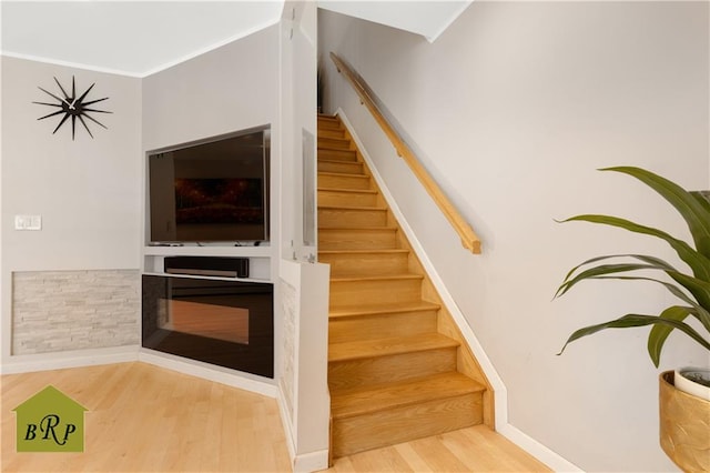 stairway featuring ornamental molding, wood finished floors, and baseboards