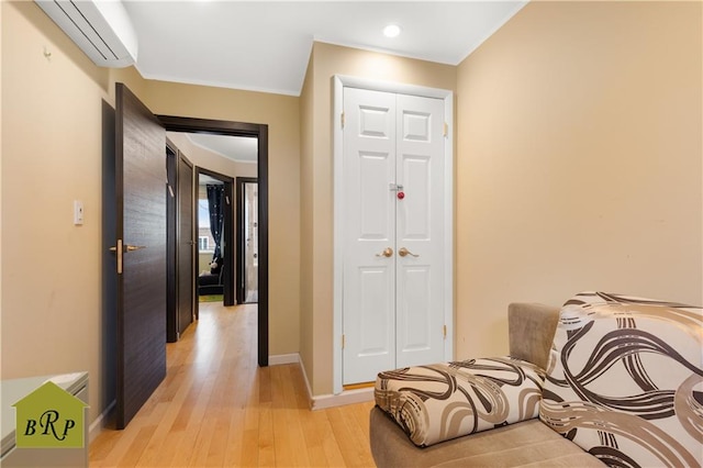 corridor featuring a wall mounted air conditioner, light wood finished floors, recessed lighting, and baseboards