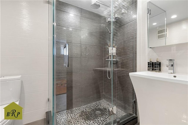 full bathroom with tile walls, a stall shower, toilet, and vanity