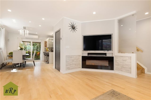 living area with stairway, wood finished floors, a notable chandelier, and ornamental molding