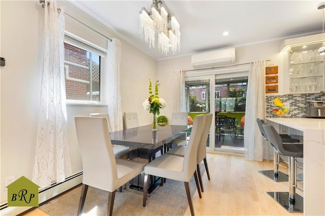 dining area with a healthy amount of sunlight, light wood-type flooring, a notable chandelier, and a wall mounted AC