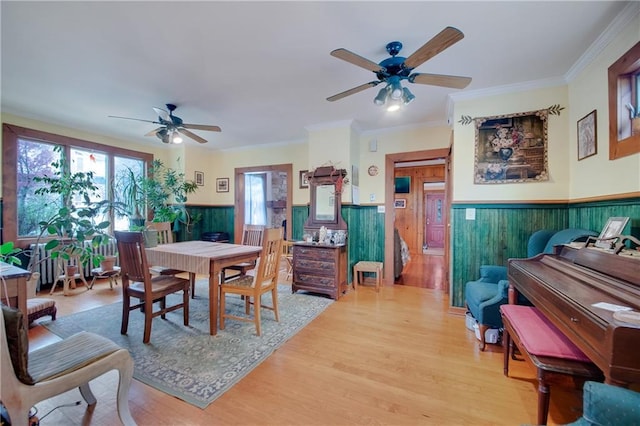 447 Greeley Ave, Staten Island, NY 10306 - dining area featuring a ceiling fan, a wainscoted wall, light wood finished floors, crown molding, and wood walls