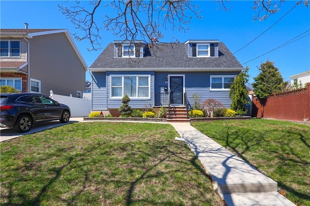 bungalow-style home with fence, roof with shingles, and a front lawn