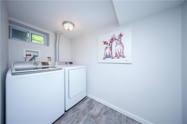 clothes washing area featuring baseboards, laundry area, wood finished floors, and washer and dryer
