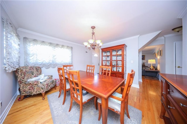 dining space with light wood-style floors, baseboards, crown molding, and a notable chandelier