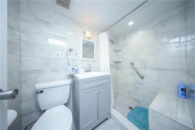 full bathroom featuring toilet, visible vents, a tile shower, and vanity