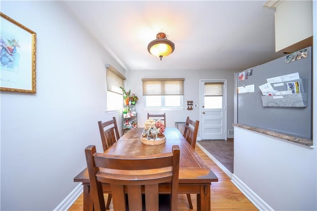 dining space with light wood-type flooring and baseboards