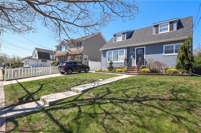 view of front facade featuring central AC, roof with shingles, fence, and a front yard