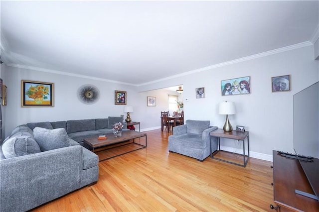 living room featuring baseboards, ornamental molding, and light wood finished floors