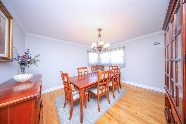 dining area featuring ornamental molding, light wood-style flooring, and a notable chandelier