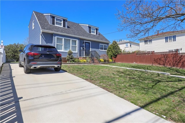view of front of home featuring roof with shingles, fence, driveway, and a front yard