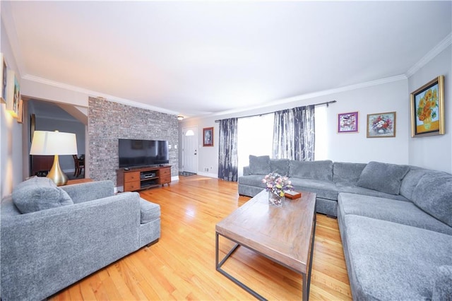 living area with baseboards, ornamental molding, and light wood-style flooring