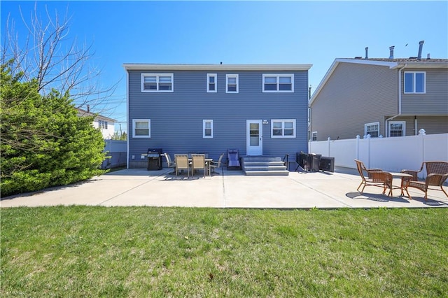 rear view of house with a lawn, a patio, and fence