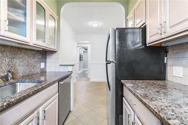 1500 Ocean Pkwy Unit 4G, Brooklyn, NY 11230 - kitchen with arched walkways, appliances with stainless steel finishes, decorative backsplash, light tile patterned flooring, and dark stone counters