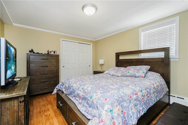 bedroom featuring crown molding, a closet, wood finished floors, and baseboard heating