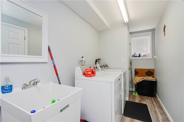 laundry room featuring baseboards, a sink, laundry area, light wood finished floors, and washing machine and clothes dryer