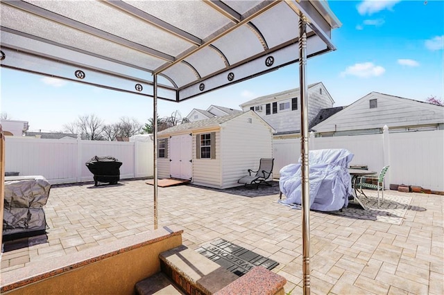 view of patio / terrace with outdoor dining space, a storage shed, a fenced backyard, and an outdoor structure