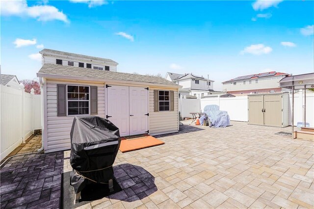 exterior space with grilling area, an outbuilding, a fenced backyard, and a shed