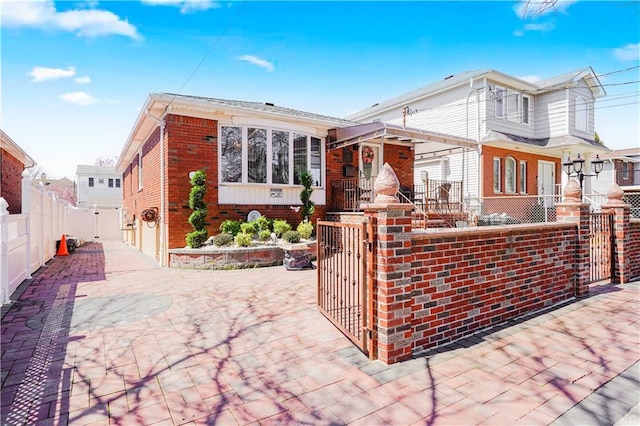 view of front of property featuring brick siding, a gate, and a fenced front yard