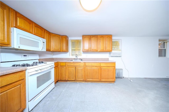 kitchen with white appliances, radiator heating unit, light countertops, a sink, and brown cabinetry