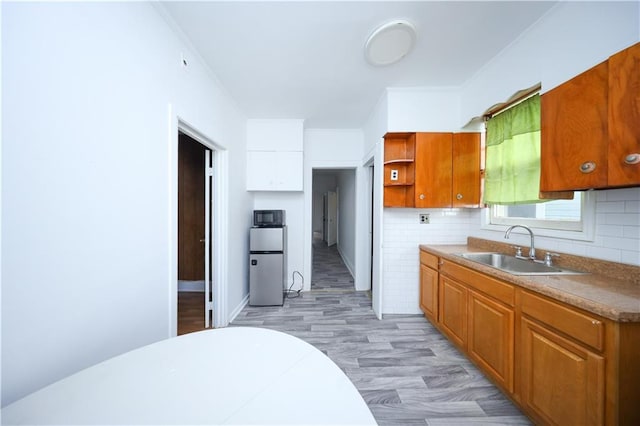 kitchen featuring a sink, open shelves, brown cabinetry, and backsplash