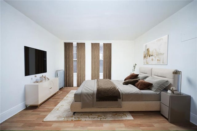 bedroom featuring radiator heating unit, baseboards, and wood finished floors