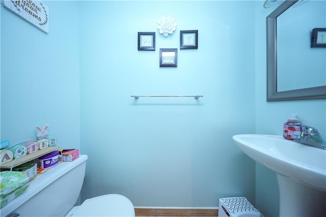 bathroom featuring toilet, a sink, and baseboards