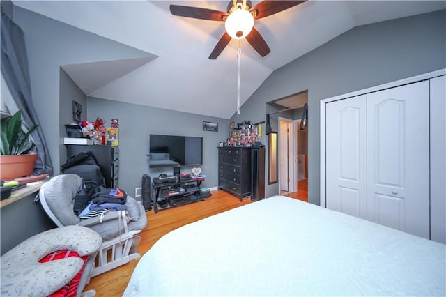 bedroom with a closet, a ceiling fan, vaulted ceiling, and light wood-type flooring