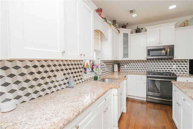 kitchen with white cabinetry, backsplash, visible vents, appliances with stainless steel finishes, and a sink