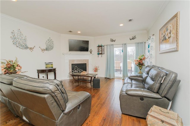 living area with crown molding, wood finished floors, and a fireplace