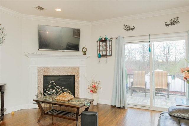 living room with visible vents, baseboards, ornamental molding, wood finished floors, and a glass covered fireplace