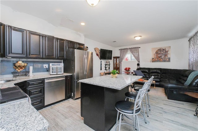 kitchen featuring tasteful backsplash, light wood-type flooring, a breakfast bar, stainless steel appliances, and a kitchen island