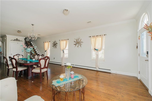 dining space featuring an inviting chandelier, baseboard heating, crown molding, wood finished floors, and stairs