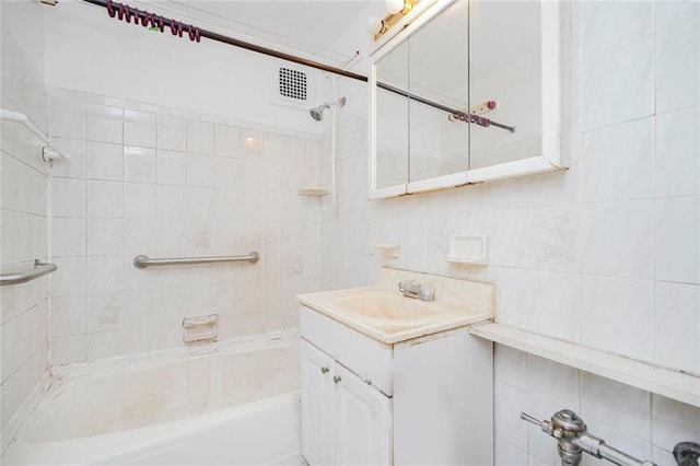 bathroom featuring tile walls,  shower combination, and vanity