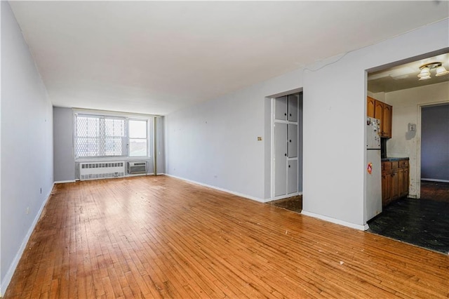 1580 E 13th St Unit 5C, Brooklyn, NY 11230 - empty room with radiator heating unit, hardwood / wood-style flooring, baseboards, and a wall mounted air conditioner