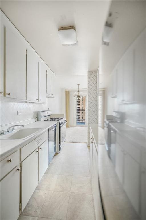 kitchen featuring light countertops, a notable chandelier, a sink, and gas range