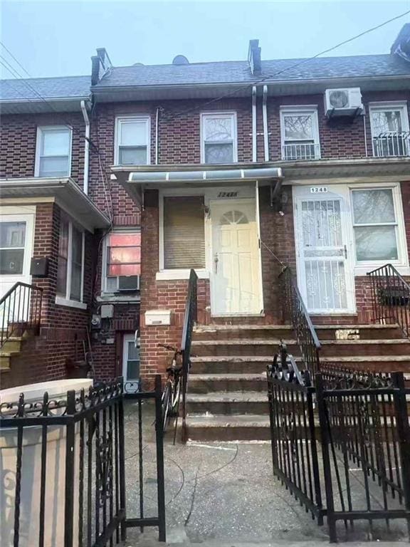 multi unit property featuring brick siding, a fenced front yard, and entry steps