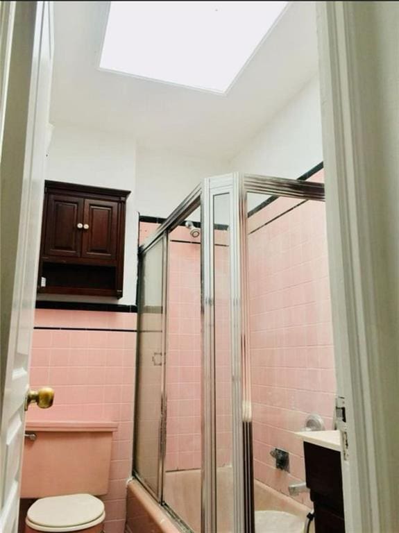 bathroom with toilet, tile walls, and a stall shower