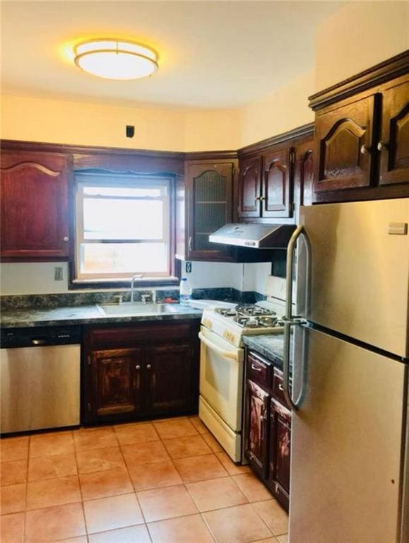kitchen featuring dark countertops, ventilation hood, a sink, light tile patterned floors, and stainless steel appliances