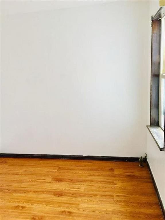 unfurnished room with baseboards and light wood-style flooring