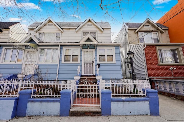 townhome / multi-family property featuring a fenced front yard and entry steps