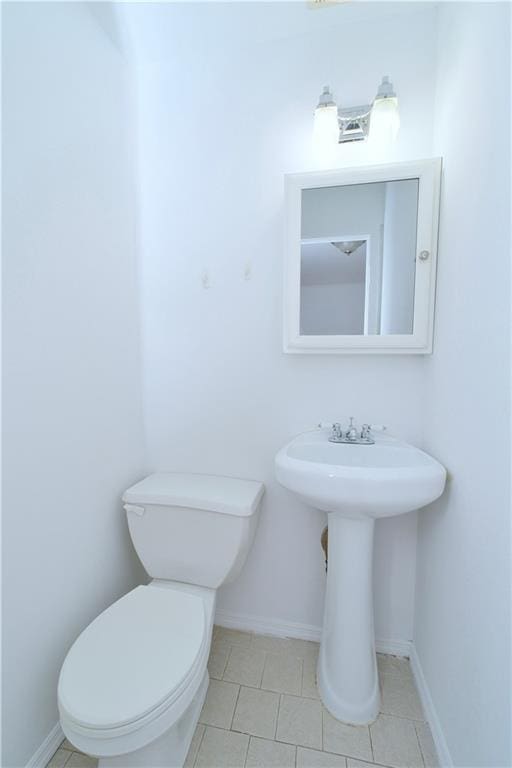bathroom featuring toilet, baseboards, and tile patterned flooring