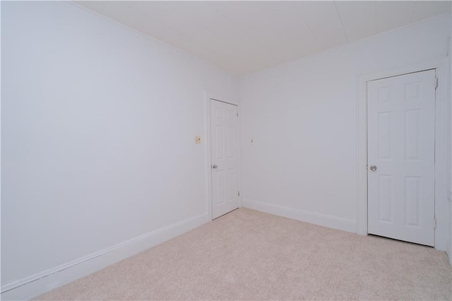 unfurnished room featuring light carpet and baseboards