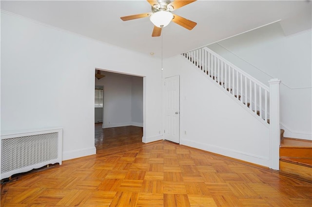 unfurnished room with radiator heating unit, stairway, a ceiling fan, and baseboards
